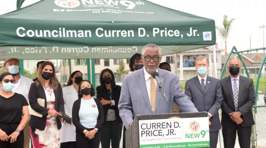 Councilman Curren D. Price speaking and several people behind him.